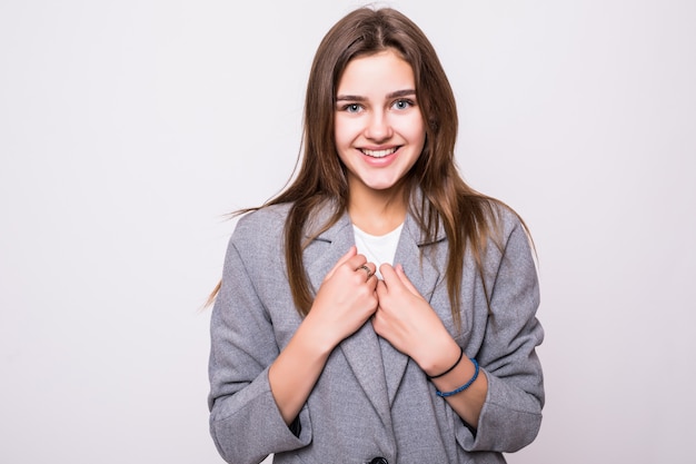 Ritratto di una donna sorridente graziosa che propone su una priorità bassa bianca