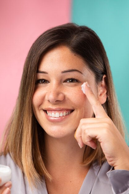 Ritratto di una donna splendida che applica una crema idratante