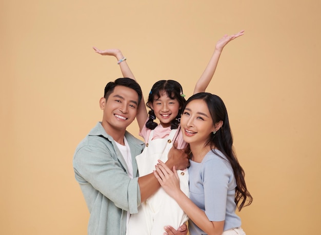 Ritratto di una famiglia asiatica felice e sorridente che si abbraccia e ama insieme isolata su uno sfondo a colori nudi
