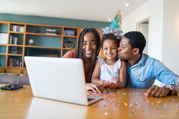 Ritratto di una famiglia che festeggia il compleanno online durante una videochiamata con la famiglia e gli amici restando a casa