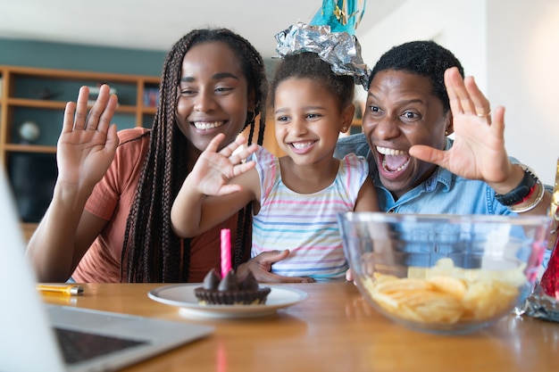 Ritratto di una famiglia che festeggia il compleanno online su una videochiamata mentre si è a casa