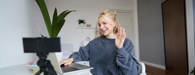 Foto gratuito ritratto di una giovane creatrice di contenuti sui social media, una donna seduta in una stanza con un portatile e una fotocamera digitale