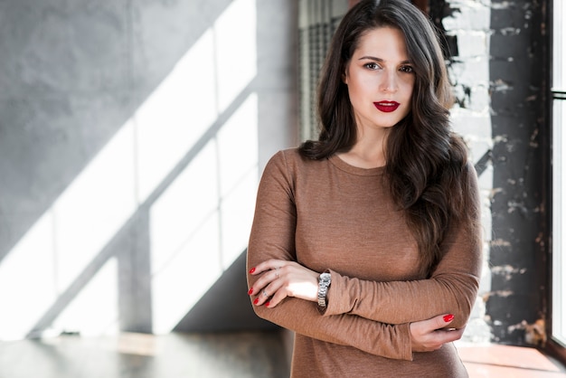 Ritratto di una giovane donna alla moda con i capelli lunghi bruna guardando la fotocamera