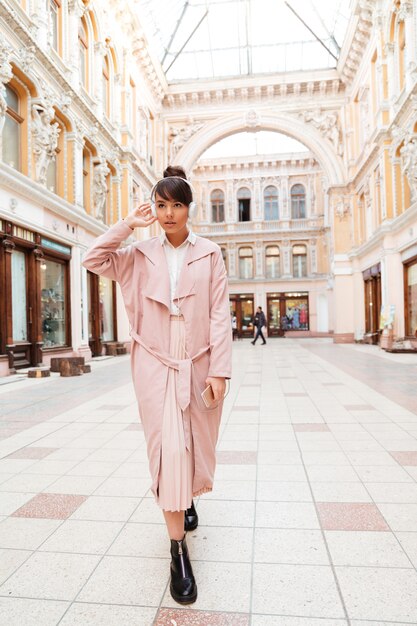 Ritratto di una giovane donna alla moda in cappotto rosa