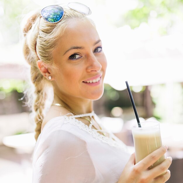 Ritratto di una giovane donna attraente che tiene vetro di latte macchiato
