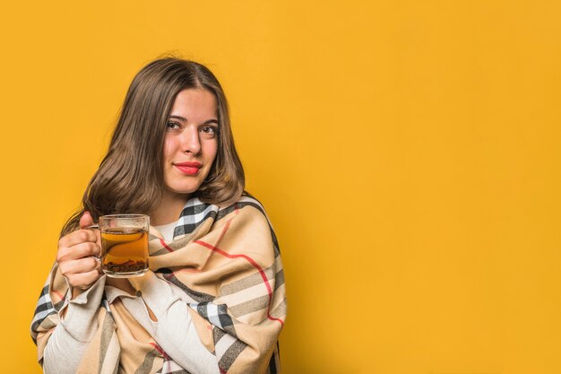 Ritratto di una giovane donna avvolta in scialle tenendo la tazza di tisana