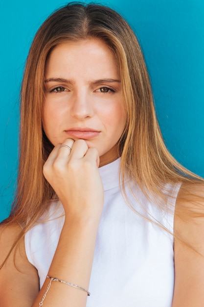 Ritratto di una giovane donna bionda che guarda l&#39;obbiettivo su sfondo blu