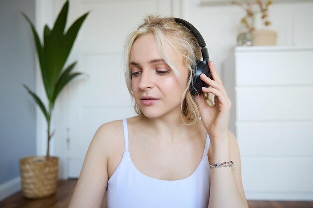 Ritratto di una giovane donna bionda di bell'aspetto con le cuffie wireless che ascolta il podcast o il favorito