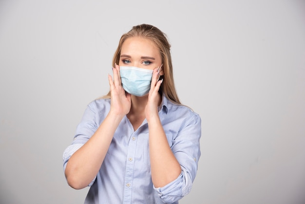 Ritratto di una giovane donna bionda in piedi con una maschera medica