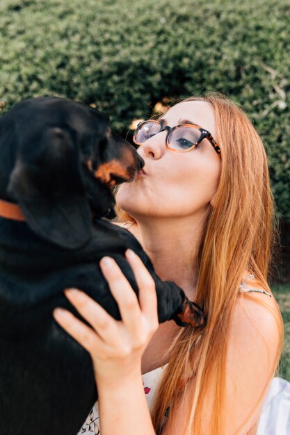 Ritratto di una giovane donna che indossa gli occhiali bacia il suo cane