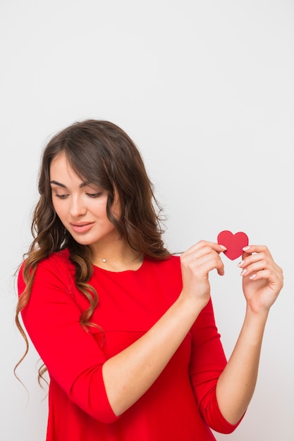 Ritratto di una giovane donna che mostra la carta di forma del cuore isolata su fondo bianco