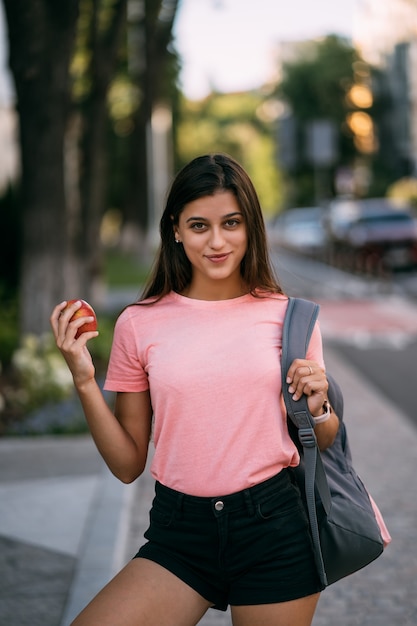 Ritratto di una giovane donna che tiene una mela su uno sfondo di strada