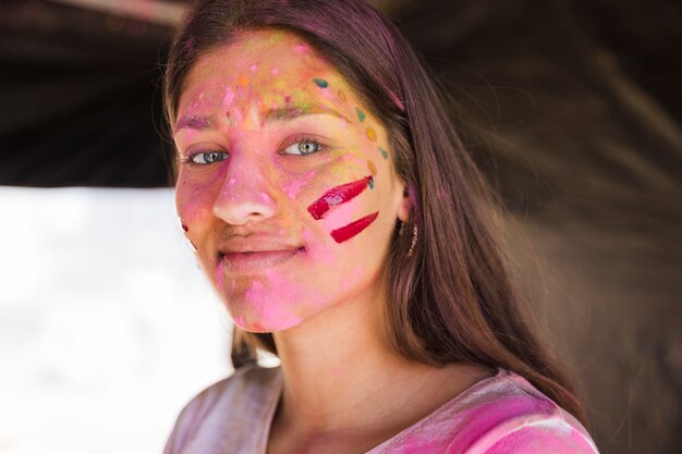 Ritratto di una giovane donna con la faccia dipinta con colori holi