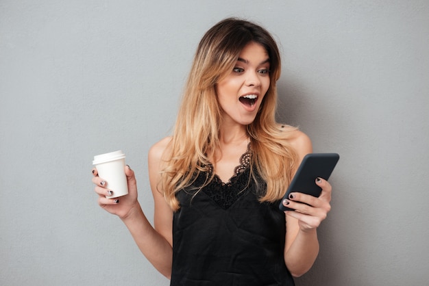 Ritratto di una giovane donna eccitata guardando il telefono cellulare