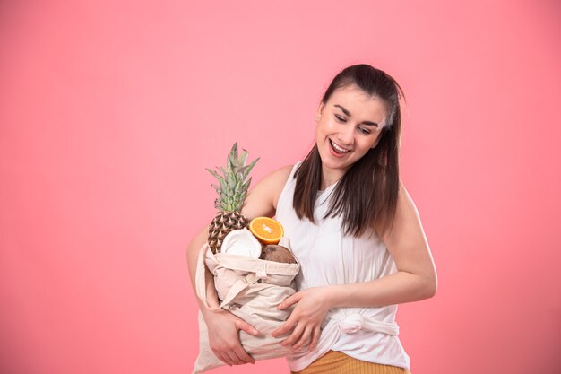 Ritratto di una giovane donna elegante con un sacchetto di frutta ecologica.