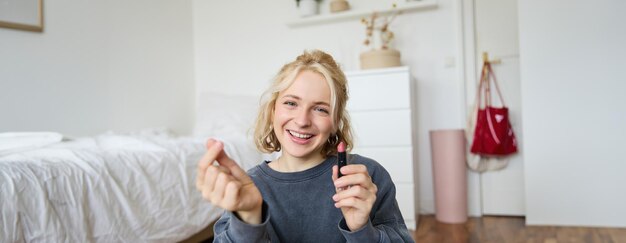 Ritratto di una giovane donna felice creatrice di contenuti multimediali che registra un vlog sul trucco nella sua stanza usando