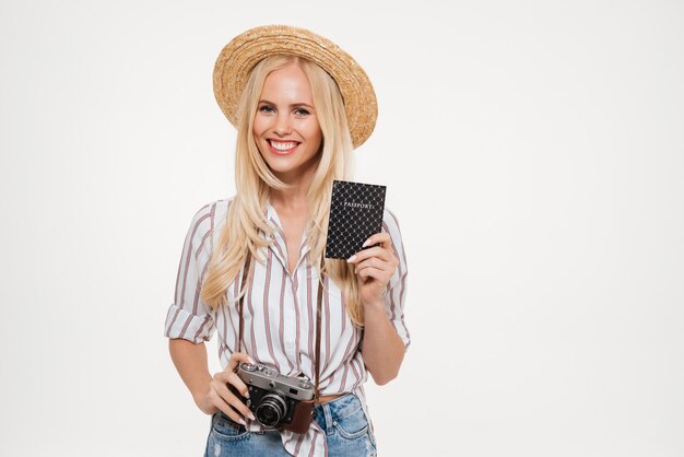 Ritratto di una giovane donna felice nella macchina fotografica della tenuta del cappello