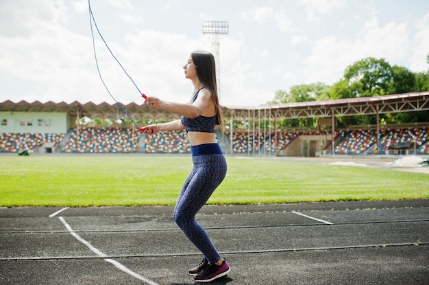 Ritratto di una giovane donna in forma felice in abbigliamento sportivo che fa esercizi con la corda per saltare