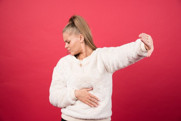 Ritratto di una giovane donna in piedi e in posa su un muro rosso