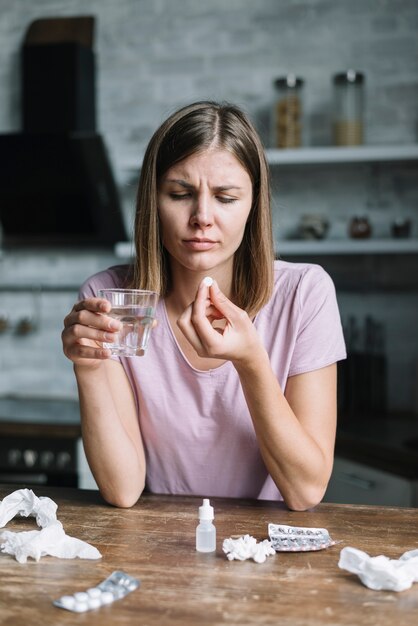 Ritratto di una giovane donna malata con bicchiere d&#39;acqua e medicina