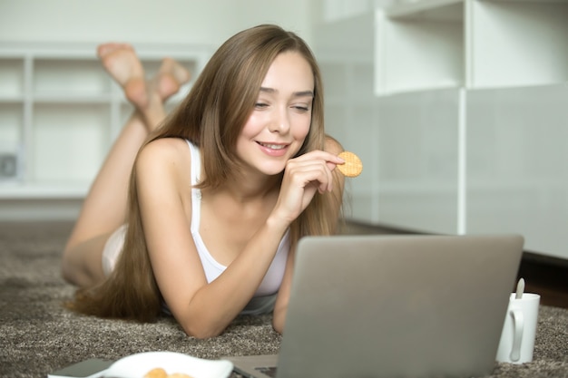 Ritratto di una giovane donna, mentendo, guardando al computer portatile