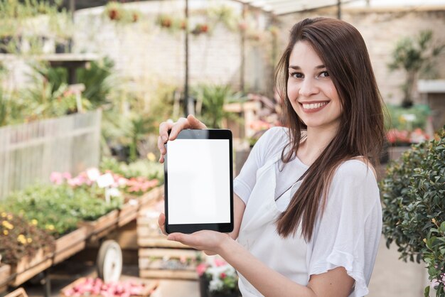 Ritratto di una giovane donna sorridente che tiene compressa digitale con schermo bianco vuoto