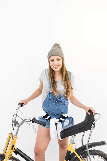 Ritratto di una giovane donna sorridente con la bicicletta su sfondo bianco