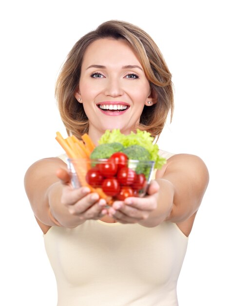 Ritratto di una giovane donna sorridente con un piatto di verdure isolato su bianco.