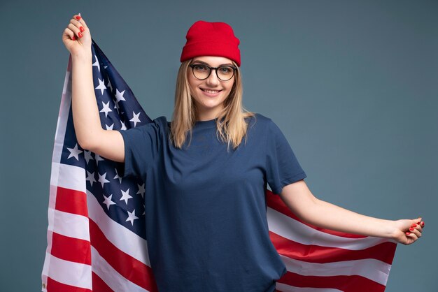 Ritratto di una giovane donna sorridente e con in mano la bandiera americana