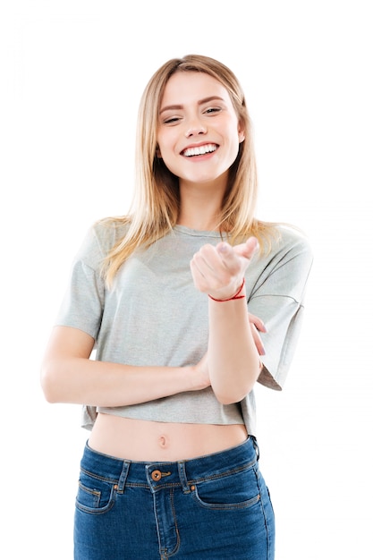 Ritratto di una giovane donna sorridente felice che indica dito alla macchina fotografica