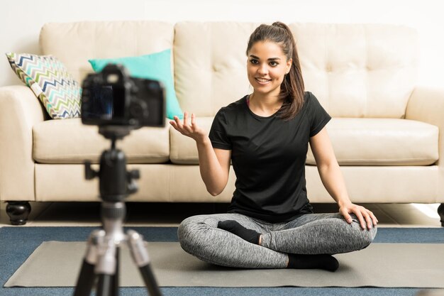 Ritratto di una giovane e bella istruttrice di yoga che registra un video per il suo blog a casa