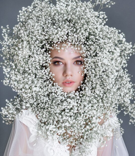 Ritratto di una giovane e bella ragazza con Cerchio fatto di gypsophila fresco sul viso vestito di camicetta bianca