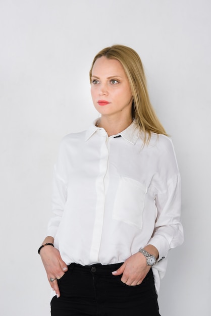 Ritratto di una giovane imprenditrice con le mani nelle tasche isolato su sfondo bianco