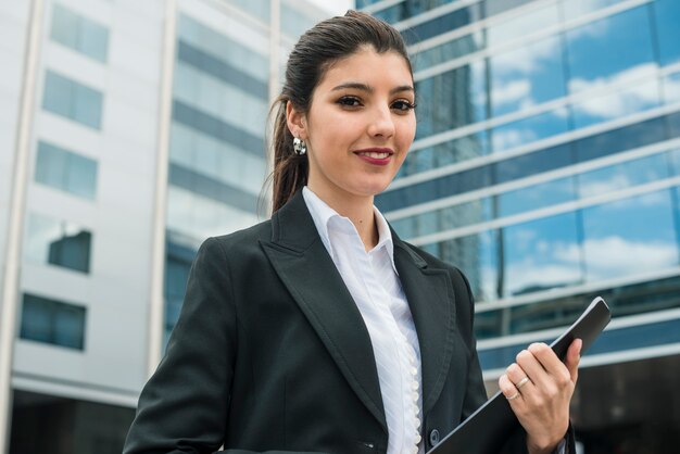 Ritratto di una giovane imprenditrice sorridente in piedi di fronte a edificio