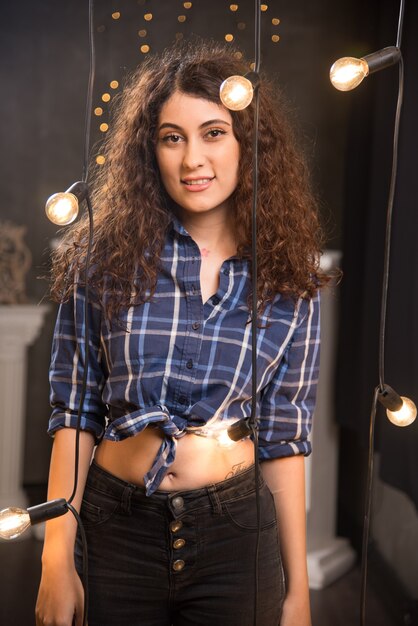 Ritratto di una giovane modella in camicia a quadri in posa vicino alle lampade