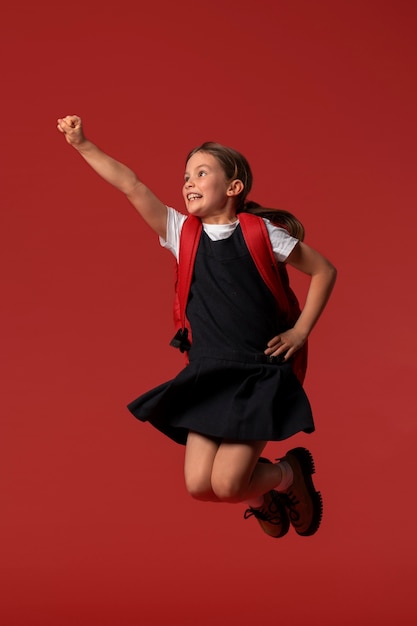 Ritratto di una giovane studentessa in uniforme scolastica che salta a mezz'aria