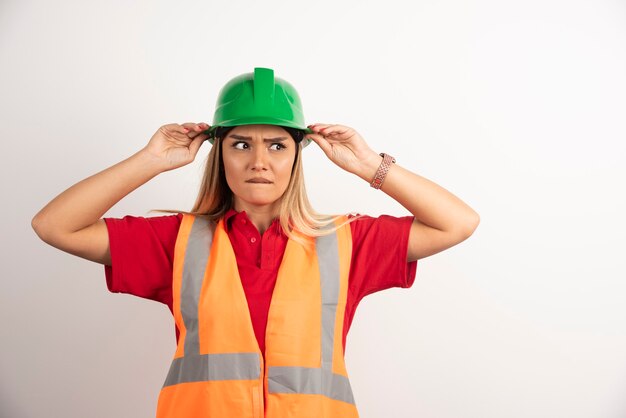 Ritratto di una lavoratrice in posa con il casco su sfondo bianco.