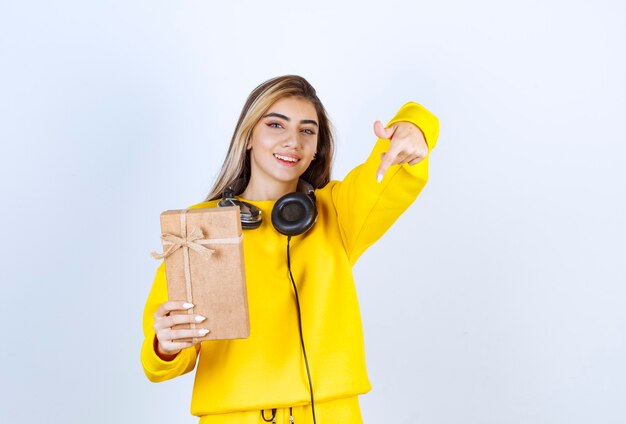 Ritratto di una modella che tiene in mano una scatola di carta con fiocco isolato su un muro bianco