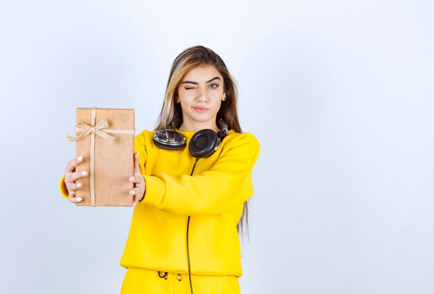 Ritratto di una modella che tiene in mano una scatola di carta con fiocco isolato su un muro bianco