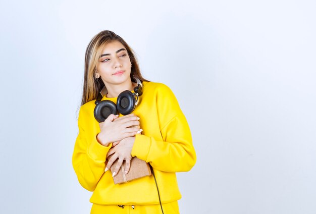 Ritratto di una modella che tiene in mano una scatola di carta con fiocco isolato su un muro bianco