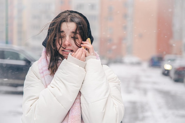 Ritratto di una ragazza adolescente all'aperto con uno smartphone in inverno nevoso