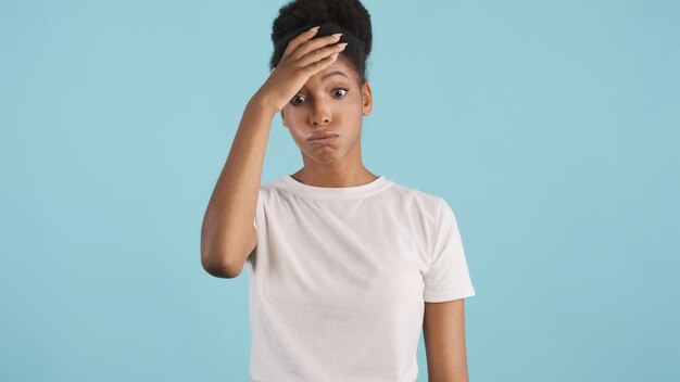 Ritratto di una ragazza afroamericana casual sconvolta che posa stancamente sulla fotocamera su sfondo colorato