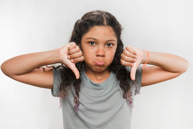 Ritratto di una ragazza arrabbiata che gesturing i pollici giù