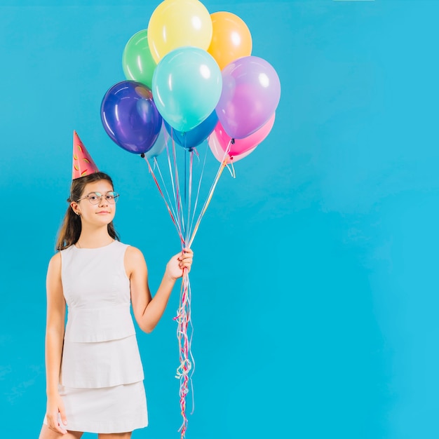 Ritratto di una ragazza che tiene palloncini colorati su sfondo blu