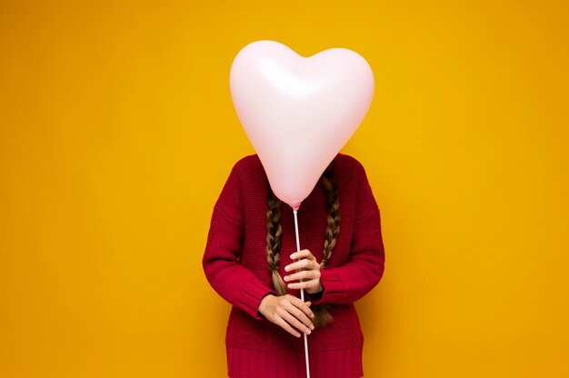 Ritratto di una ragazza che tiene un palloncino a forma di cuore davanti al viso
