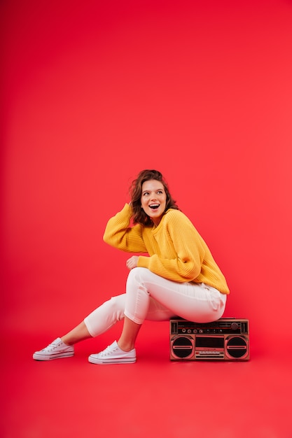 Ritratto di una ragazza felice che si siede su un boombox