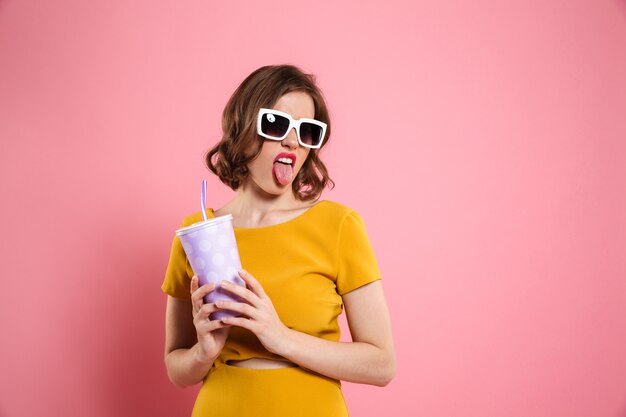 Ritratto di una ragazza funnny in occhiali da sole che tiene tazza