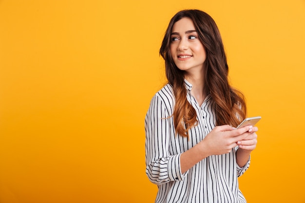 Ritratto di una ragazza graziosa che tiene telefono cellulare