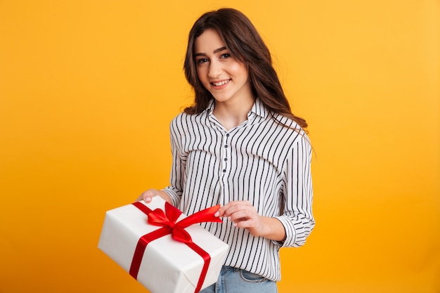 Ritratto di una ragazza sorridente che apre un contenitore di regalo