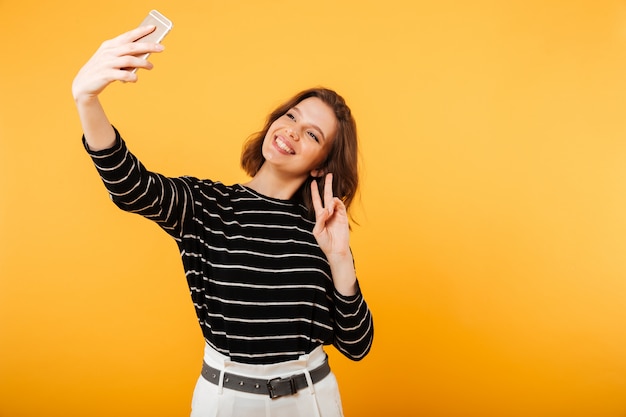 Ritratto di una ragazza sorridente che prende un selfie